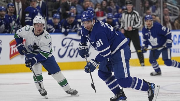 Nov 12, 2022; Toronto, Ontario, CAN; Toronto Maple Leafs forward John Tavares (91) controls the puck as Vancouver Canucks forward Nils Hoglander (21) closes in during the third period at Scotiabank Arena. Mandatory Credit: John E. Sokolowski-USA TODAY Sports